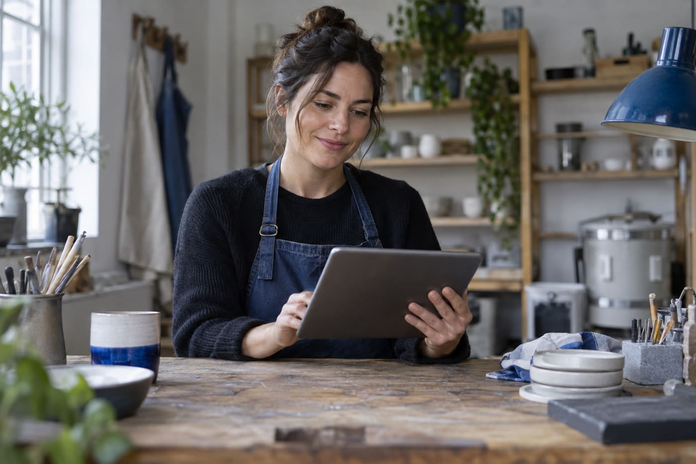 A business owner at a workshop table looking at a tablet